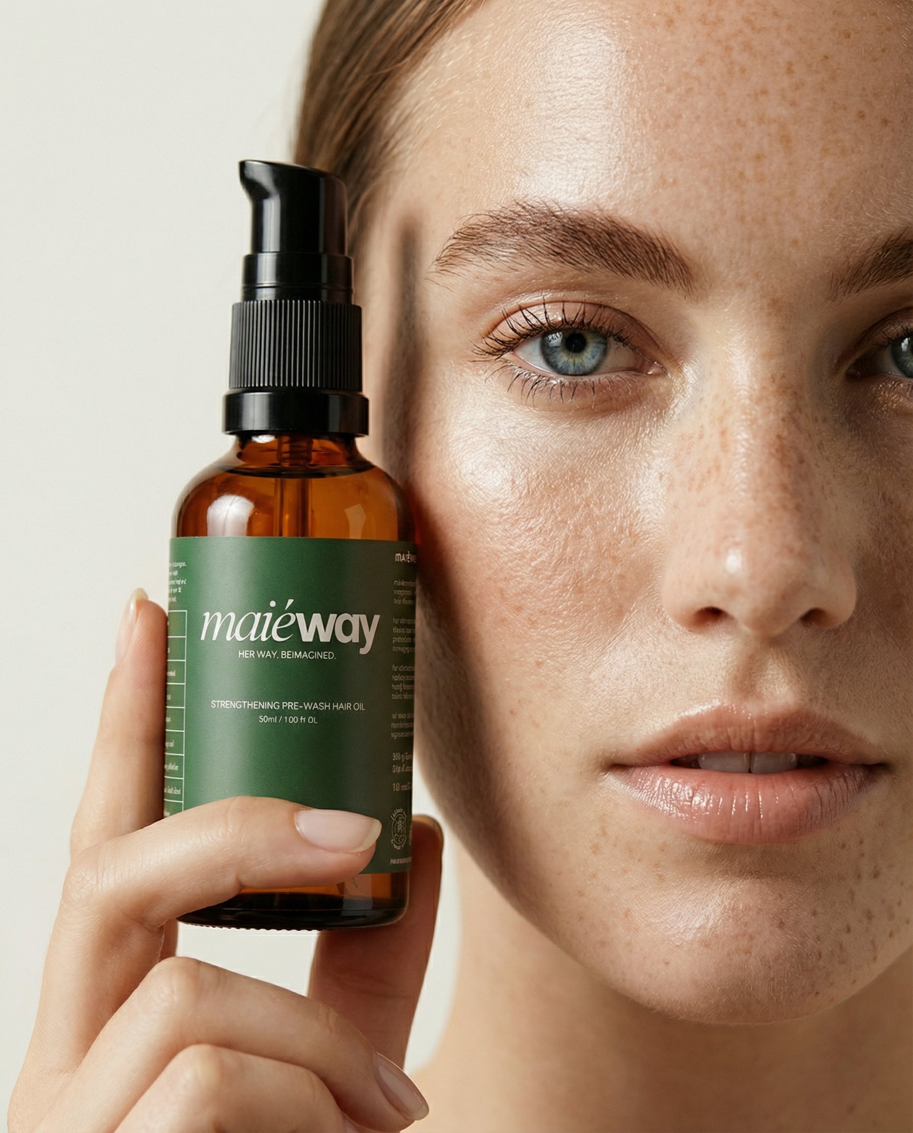 Person holding a bottle of maieway hair oil product close to their face