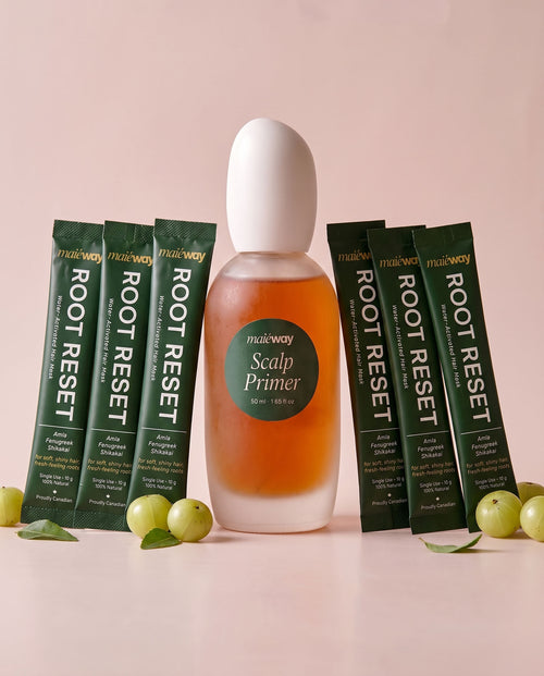 A bottle of Maieway Scalp Primer bundled with Root Reset variant flanked by six packets of the Root Reset hair mask on a soft pink background with green gooseberries as props.